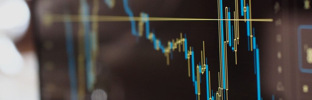 grafik harga saham dengan candlestick chart di layar komputer